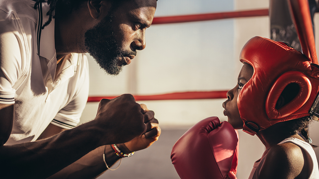 Coach teaching a student how to defend himself in the boxing ring.