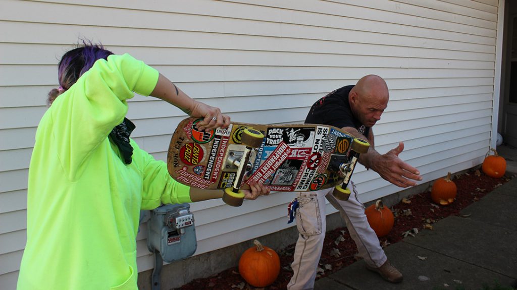 The weight of the skateboard and its metal trucks are enough to knock the knife out of her attacker’s hand.