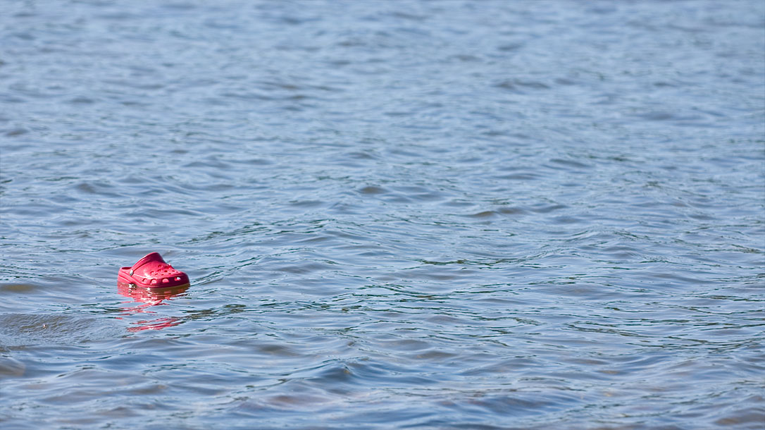 In a sea of water floats a lonely croc shoe.