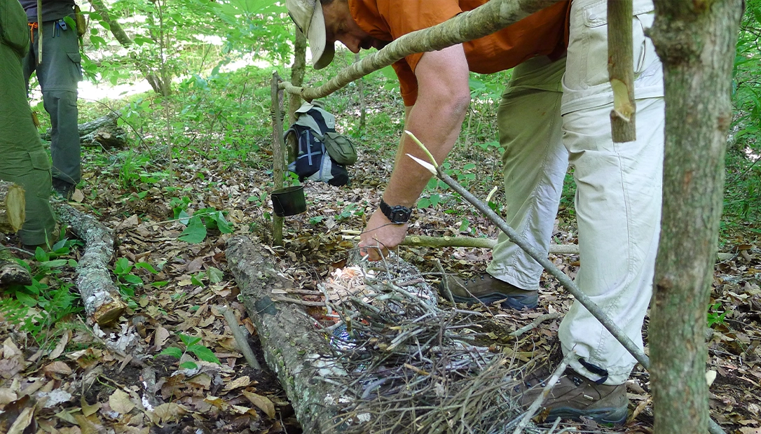 A long fire is filled in with kindling, and the end is ignited with tinder. This method allows the wind to help spread the flames into the kindling.
