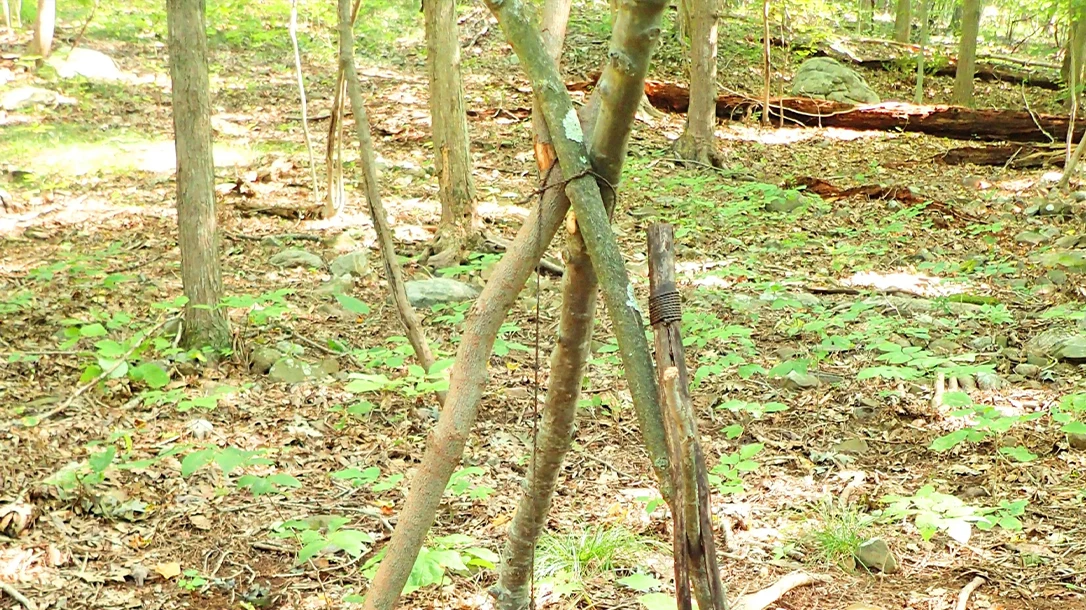 A Square Knot ties the tripod legs together. One of the legs is twisted, and a complete turn is made to provide tension. A separate rope can be used to suspend a pot or kettle from another pole.