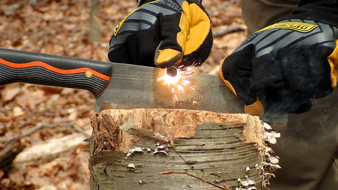 The author demonstrates the Pull-Back technique in which a blade is hammered into a stump and secured while the Ferro rod is scraped back against the 90-degree spine to produce sparks.
