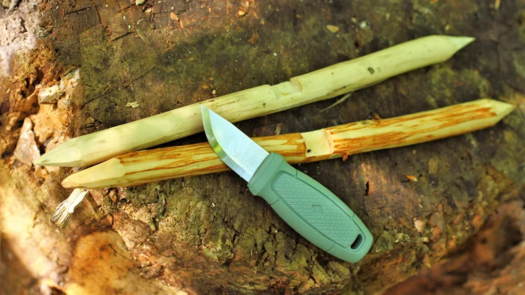 Knife Safety for Kids: The author shows making an Apache throwing star using an Eldris LightDuty. First, the bark is stripped, the ends are sharpened, and then two notches are made.