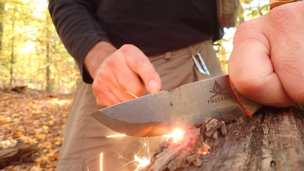 The author uses this method to strike the supplied Ferro rod against the fire notch to ignite tinder.
