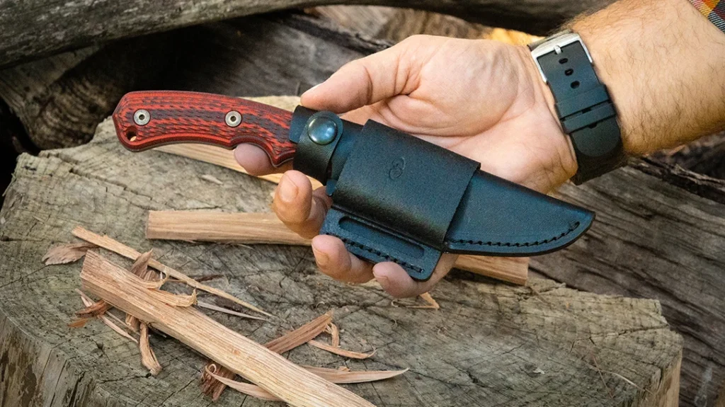 The leather sheath is a low-profile snap-retention design with a belt slot.