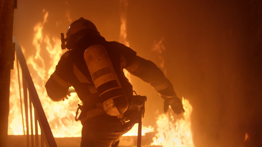 A firefighter bravely rushes into burning buildings, risking their life to save others and combat the destructive power of flames.