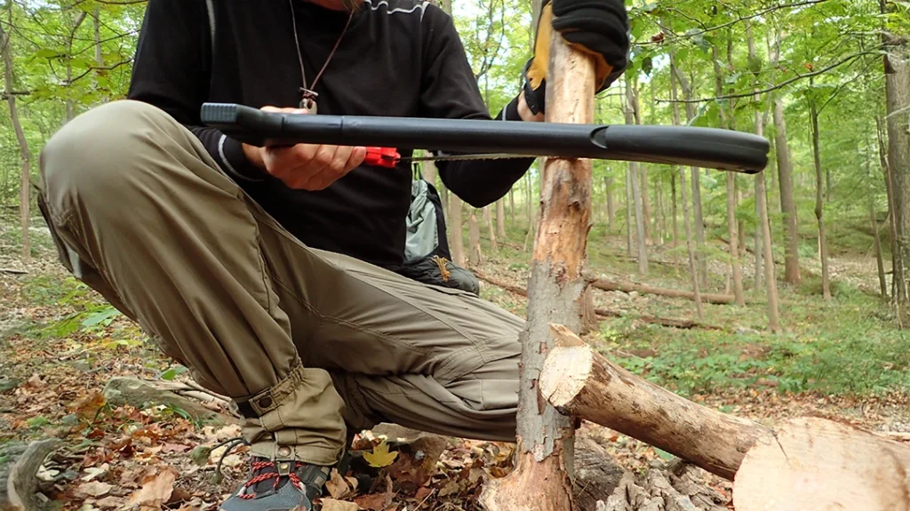 The author saws horizontally on smaller pieces of wood with the Zippo AxeSaw, rocking and moving both hands simultaneously to maximize efficiency.