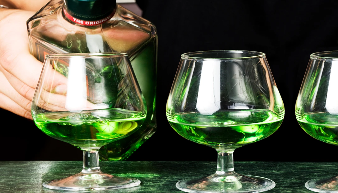 Close-up of absinthe bottle and glass.