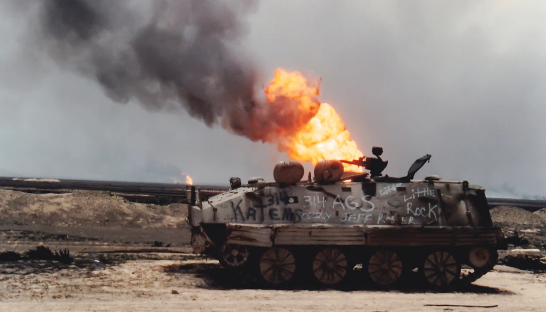 An armored tank sits burning in the Iraqi desert.