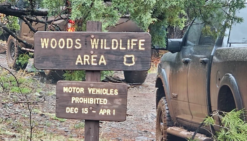Mud-covered trucks near the Woods Wildlife Area sign as the group reached the higher country.