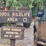 Mud-covered trucks near the Woods Wildlife Area sign as the group reached the higher country.