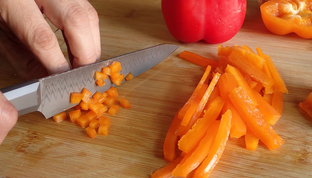 Slicing vegetables evenly with a sharp kitchen knife for meal prep.