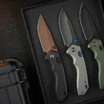 Three CIVIVI Elite Brova knives in three colors sitting on a desk.
